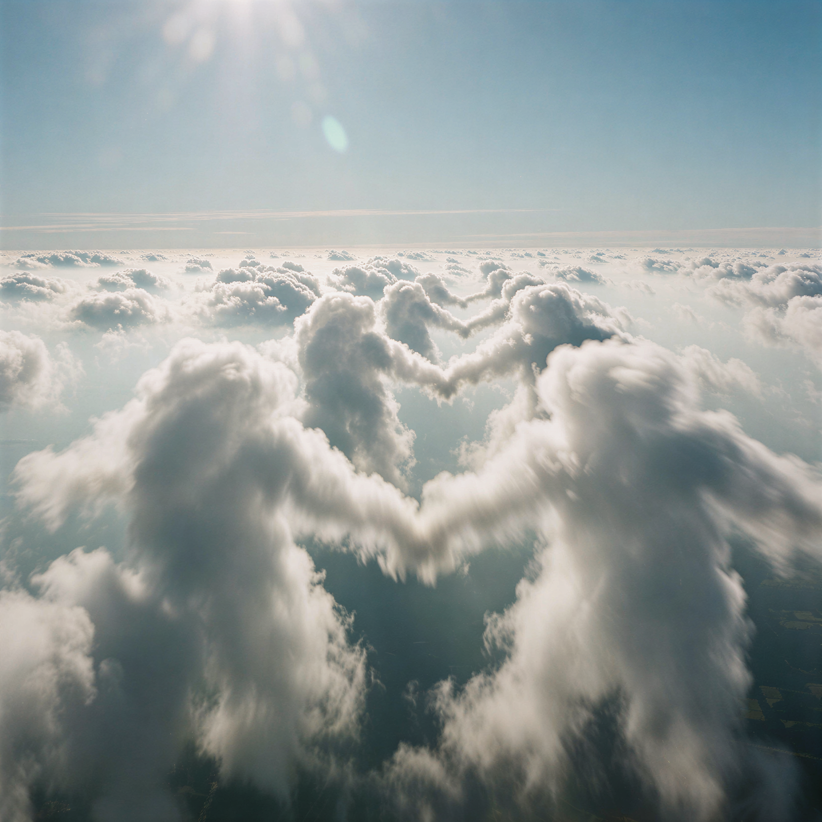 a realistic aerial photograph of dense white cumulus clouds drifting across a clear pale blue sky during the bright morning sun, the cloud formations arranged in a gentle rhythmic pattern that resembles figures dancing hand in hand, soft volumetric highlights on the upper surfaces and subtle gray shading underneath to define their three-dimensional structure, natural atmospheric perspective with slightly muted colors in the distance, captured from a high-altitude perspective looking down at an angle, shot on 35mm Kodak Portra 400 with fine visible film grain, slight lens flare from the sun, gentle motion blur on the cloud edges to suggest slow movement.